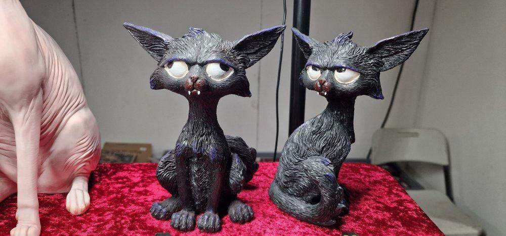 Two sculpted black cats on red velvet