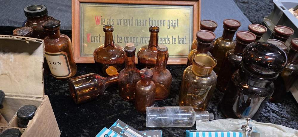 Brass sign among amber apothecary bottles