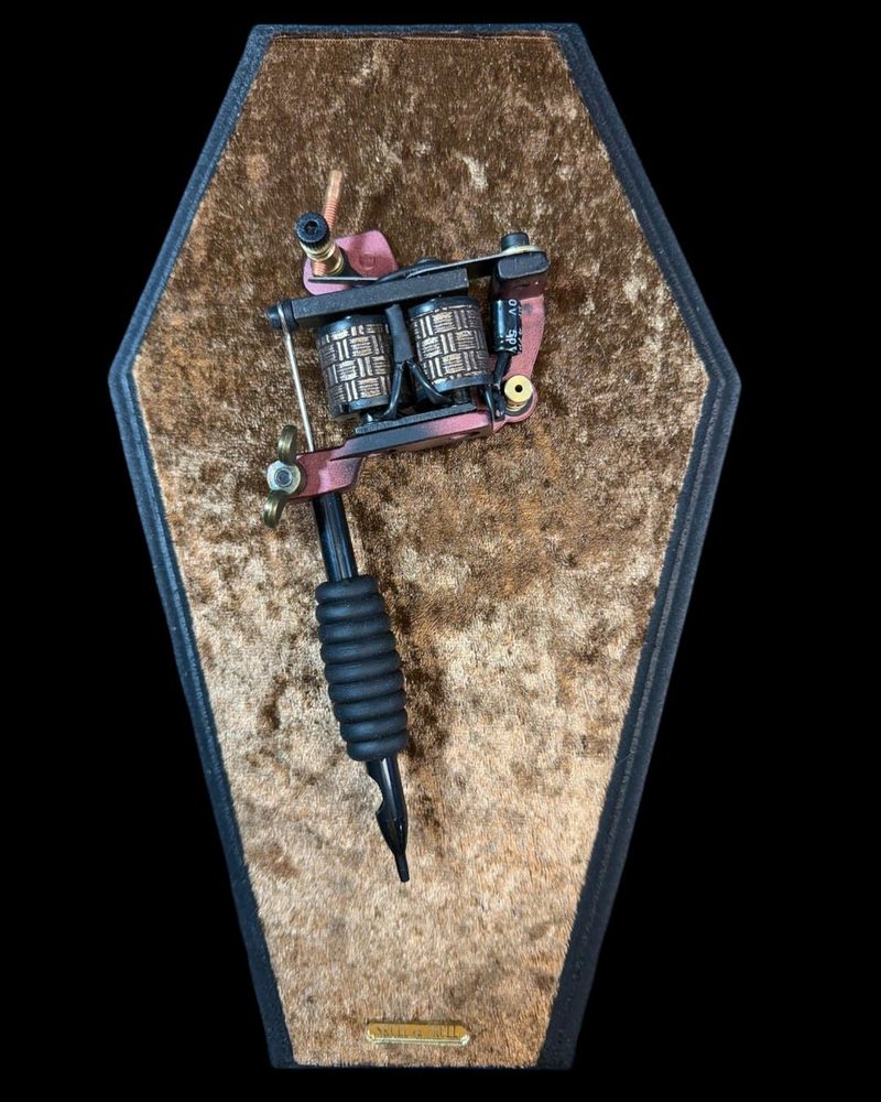 Tattoo machine in a coffin shaped frame with tan velvet